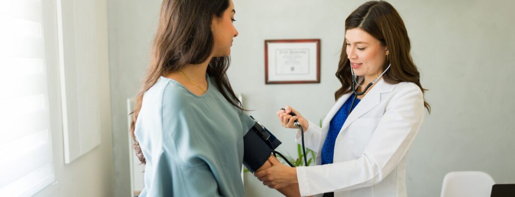 Doctor taking a patient's blood pressure during a routine check-up, symbolizing the importance of primary care in maintaining lifelong health.