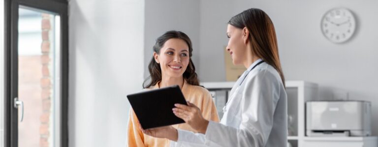 Female primary care doctor discussing health results with a smiling patient in a modern medical office.