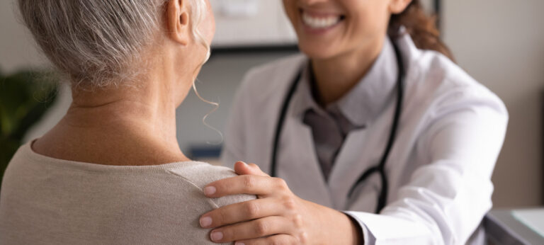 A smiling woman talks with her primary care doctor during a relaxed, routine check-up — representing the importance of preventive care and building a long-term relationship with your provider.